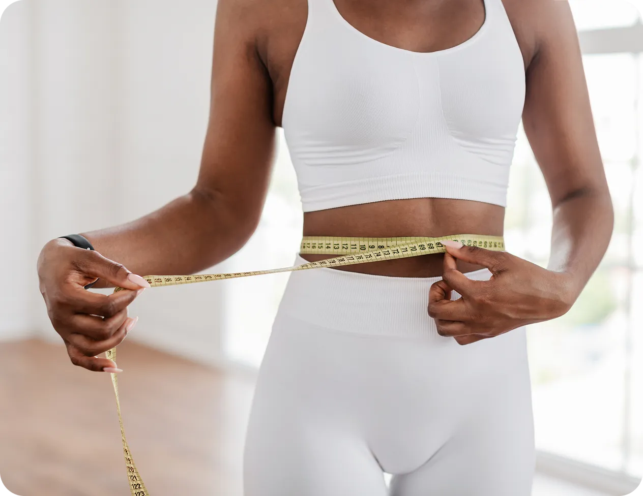 Woman measuring her waist with a tape measure